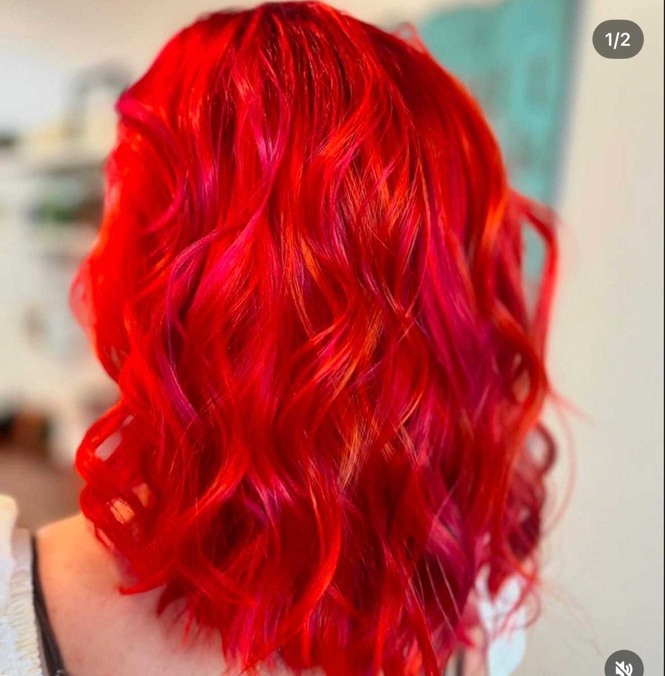 Vibrant red and pink wavy hair styled in soft curls from a rear view.