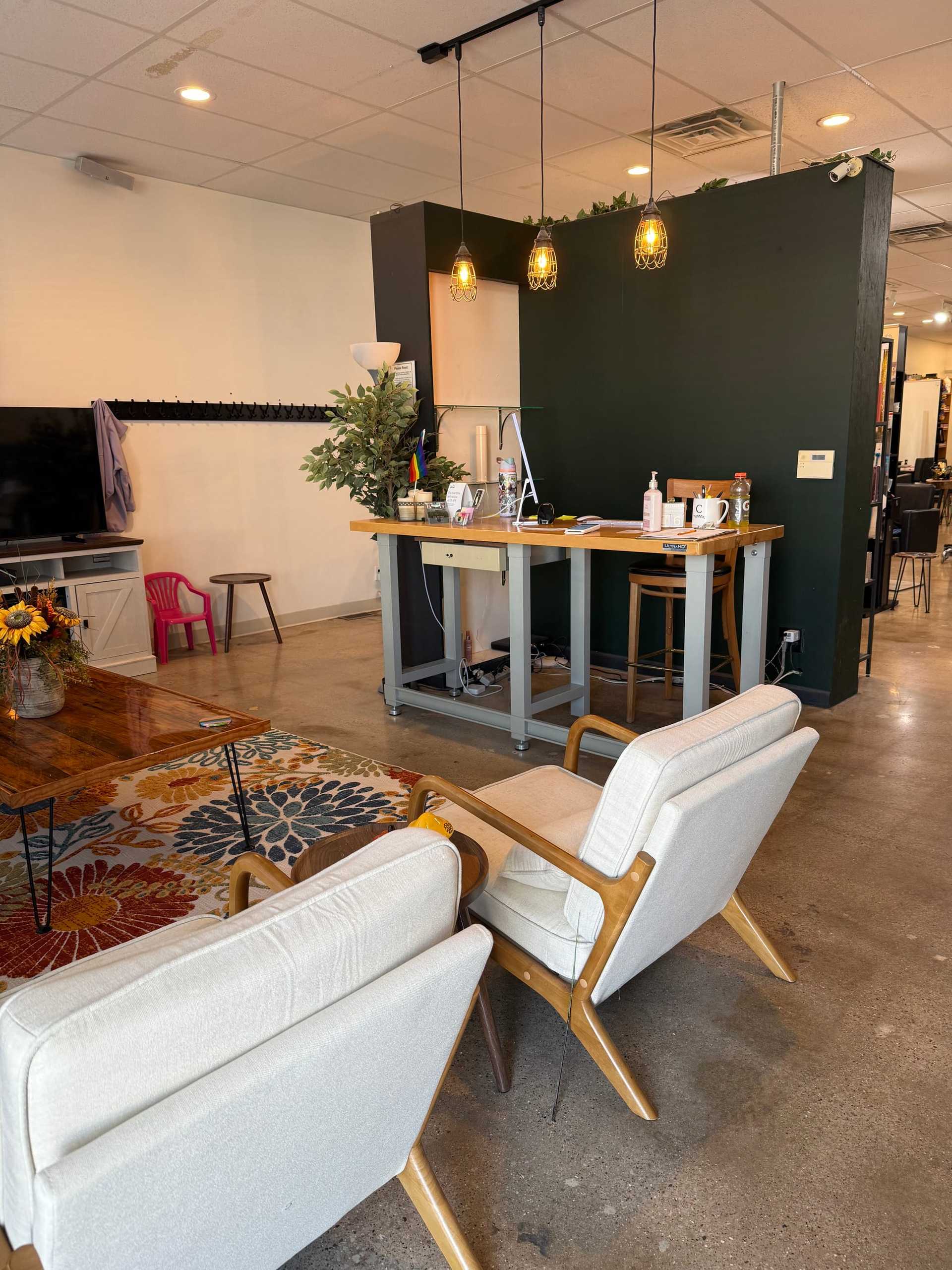 Stylish lounge area with modern chairs, vibrant rug, and a cozy coffee counter in a bright room.