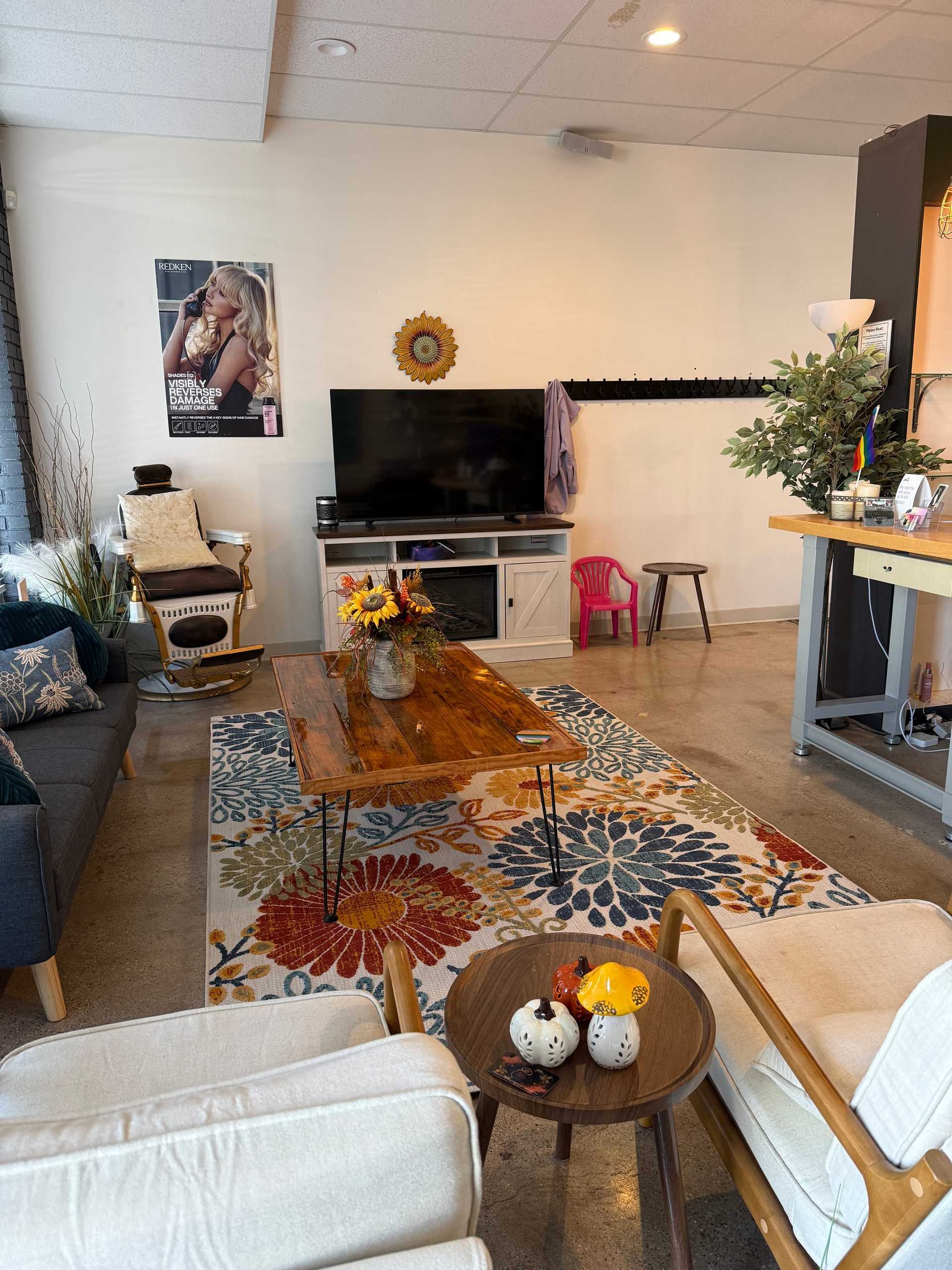 Cozy living room with a TV, sofa, armchairs, colorful rug, and autumn-themed decorations.