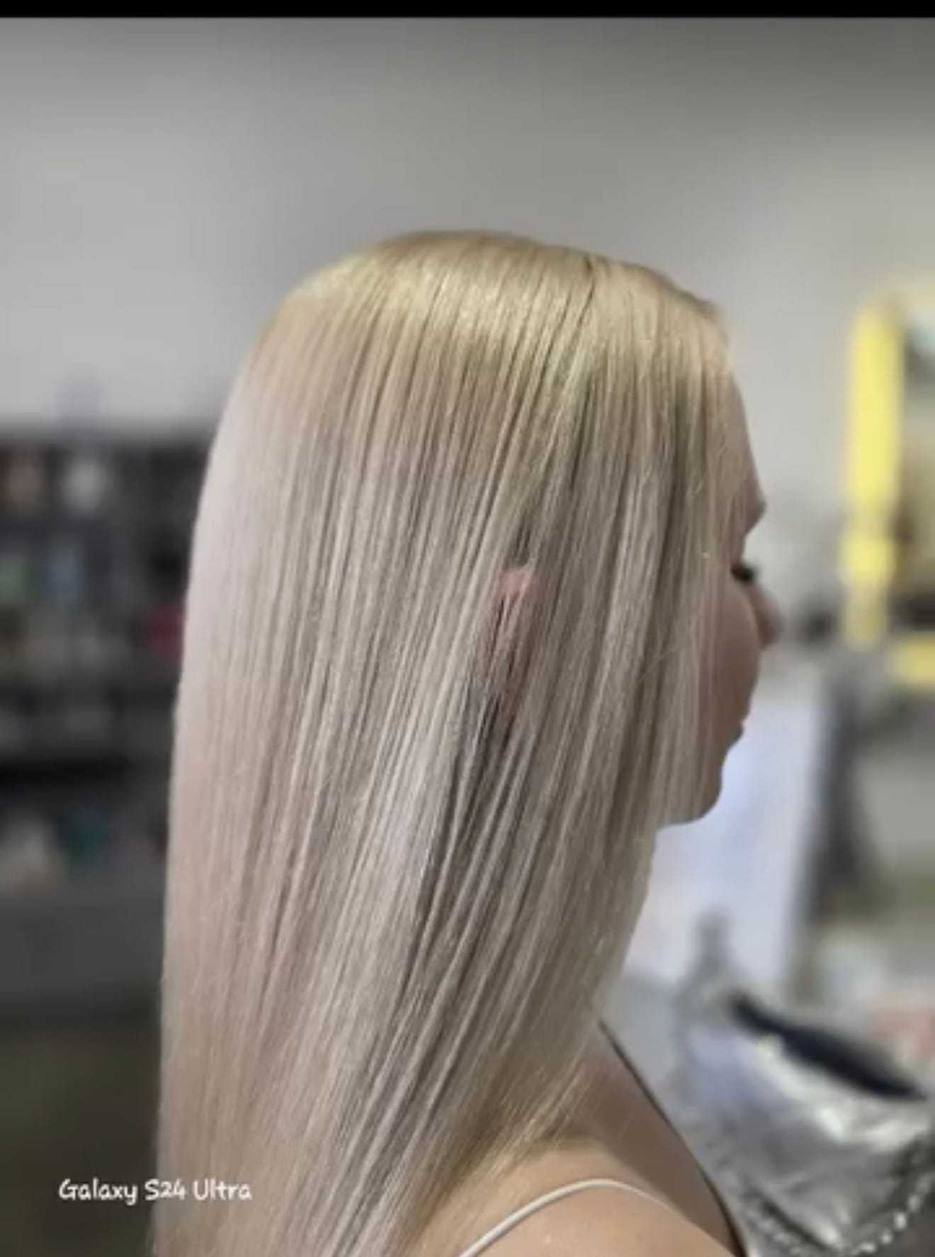 A person with straight, smooth blonde hair is shown in a salon setting.