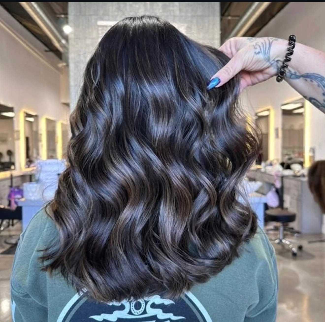 Hair with dark brown and caramel highlights styled in loose waves at a salon.